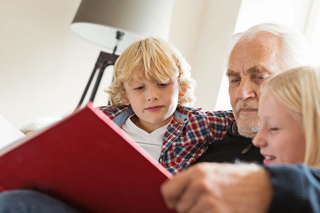 a man reading a book to his grandchildren